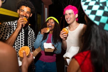 Friends eating burgers outdoors at night