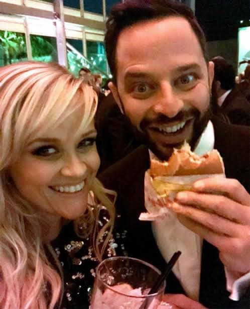 Two people at a party sharing a burger and a drink